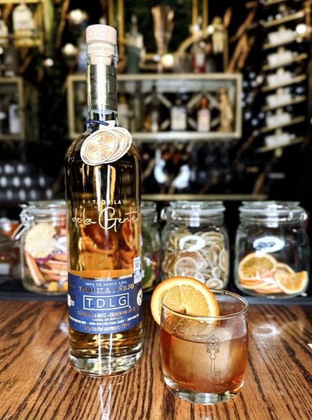 Tequila de la Gente Anejo beside an orange-garnished old fashioned