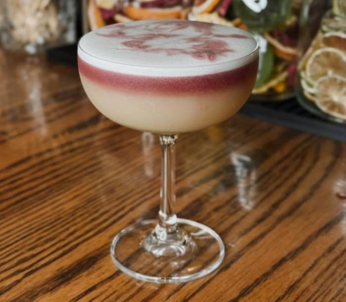 A layered sour in a coupe with a red wine float