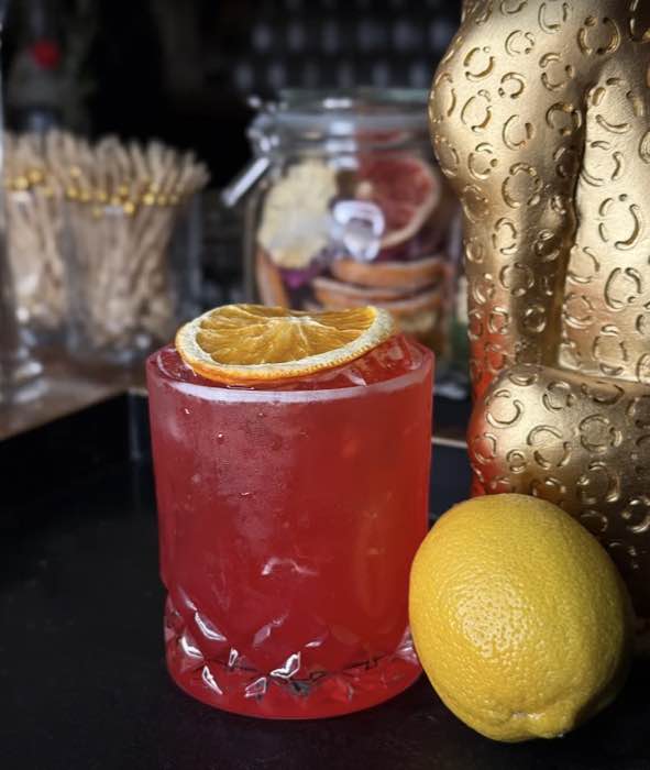 A red cocktail on the rocks beside a gilded leopard